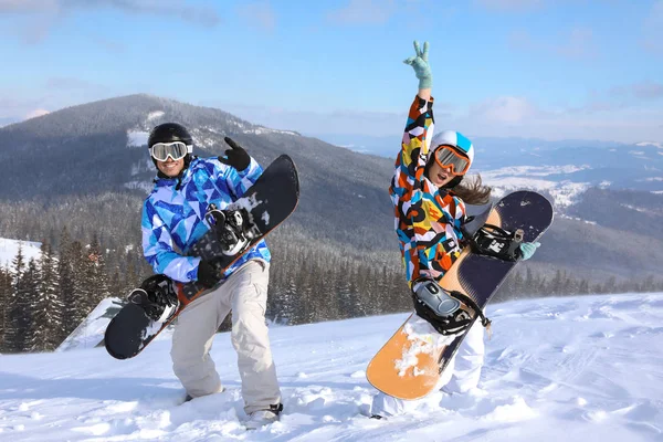 Casal com snowboards se divertindo na pista de esqui no resort nevado. Férias inverno — Fotografia de Stock