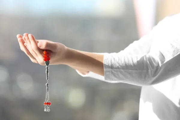 Joven musulmán con cuentas de oración haciendo tasbih sobre fondo borroso — Foto de Stock