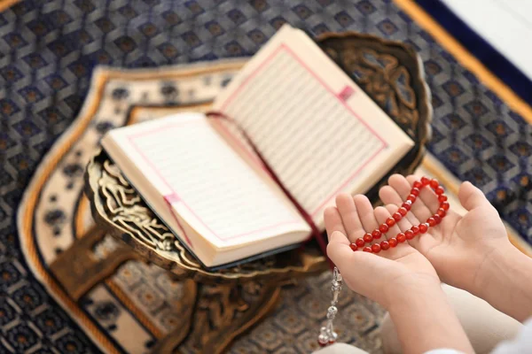 Junger muslimischer Mann mit Gebetsperlen, die Tasbih auf Teppich machen, Nahaufnahme — Stockfoto