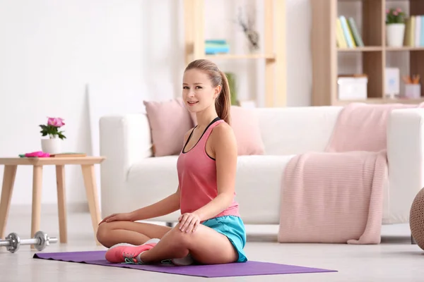 Mooie jonge vrouw ontspannen op yoga mat thuis — Stockfoto