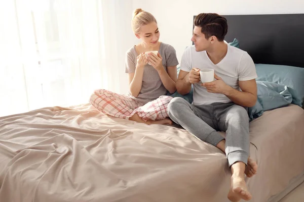 Giovane bella coppia bere caffè sul letto — Foto Stock