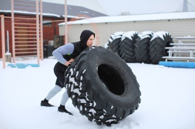 Genç kaslı adam açık havada ağır lastik, saygısız