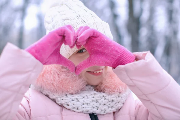 Χαριτωμένο κορίτσι δείχνει καρδιά σε ψυχρός ημέρα σε εξωτερικούς χώρους. Χειμερινές διακοπές — Φωτογραφία Αρχείου