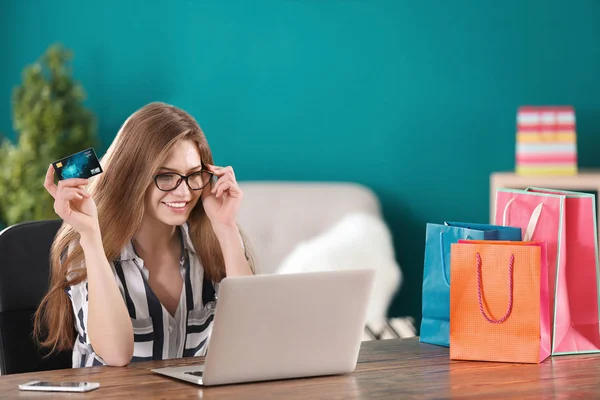 Молодая женщина делает покупки онлайн с кредитной картой и ноутбуком за столом — стоковое фото