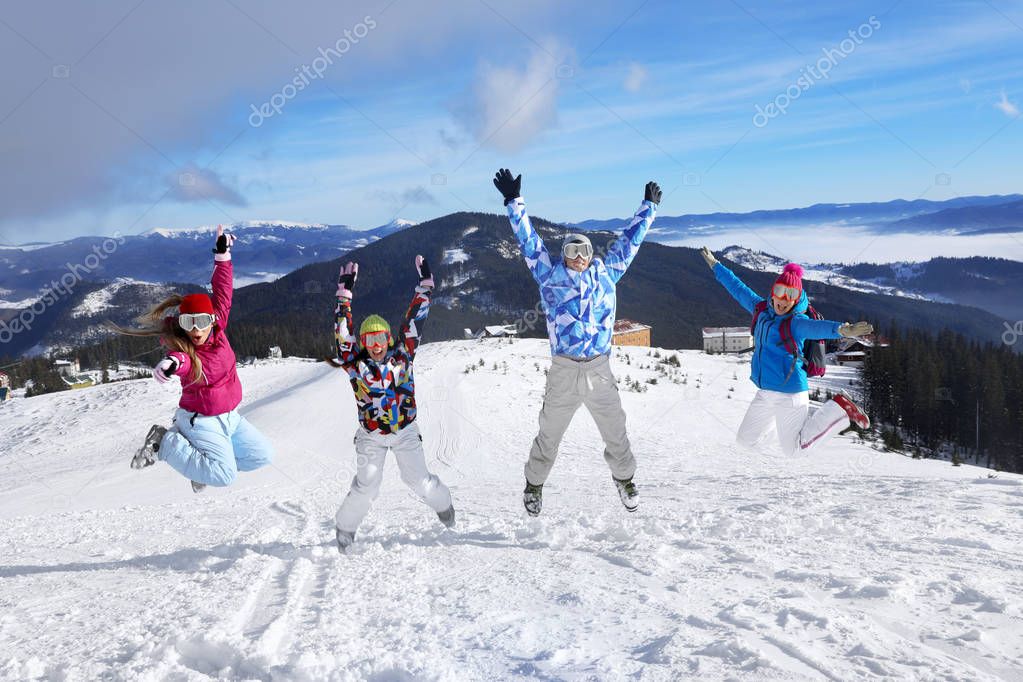 Happy friends on ski piste at snowy resort. Winter vacation