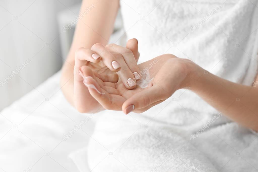 Young woman applying hand cream at home, closeup