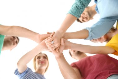 Young people putting hands together on light background. Unity concept clipart