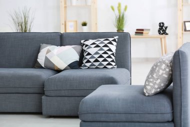 Modern grey sofa with different pillows in living room clipart