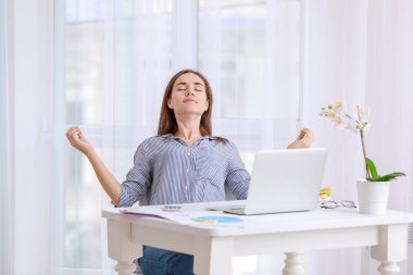 Genç kadın ofiste masasında çalışırken meditasyon