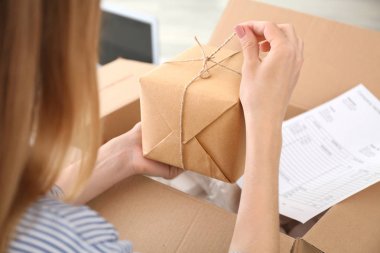 Evde paketleri açan genç bir kadın.