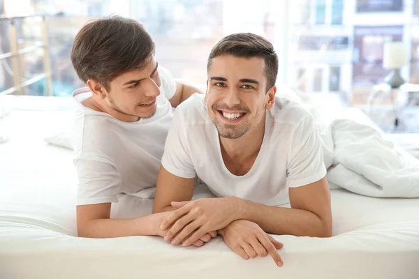 Jovem gay casal deitado no cama no casa — Fotografia de Stock