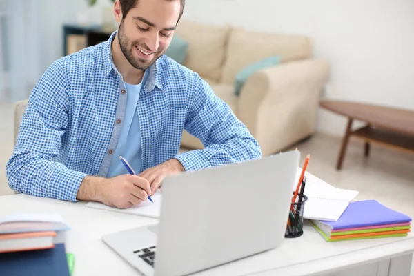 Student with laptop studying at table indoors