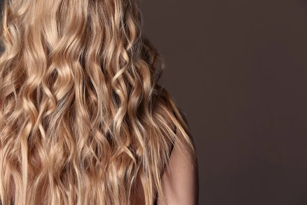 Mulher bonita com cabelo ondulado longo no fundo da cor — Fotografia de Stock