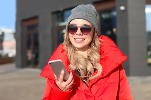 Ung kvinna i snygg outfit med mobiltelefon utomhus — Stockfoto