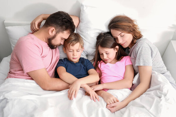 Parents and children sleeping in bed at home