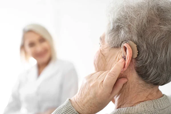 Senior woman adjusting hearing aid