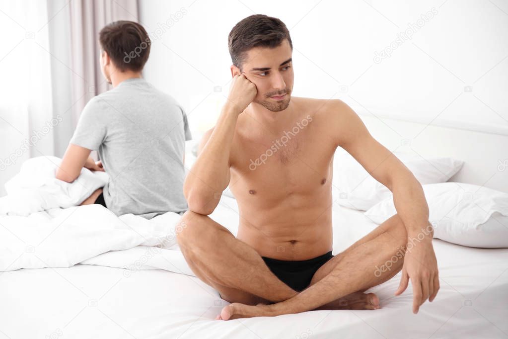 Young gay couple with relationship problems on bed