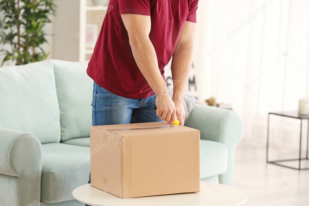 Young man unpacking parcel at home