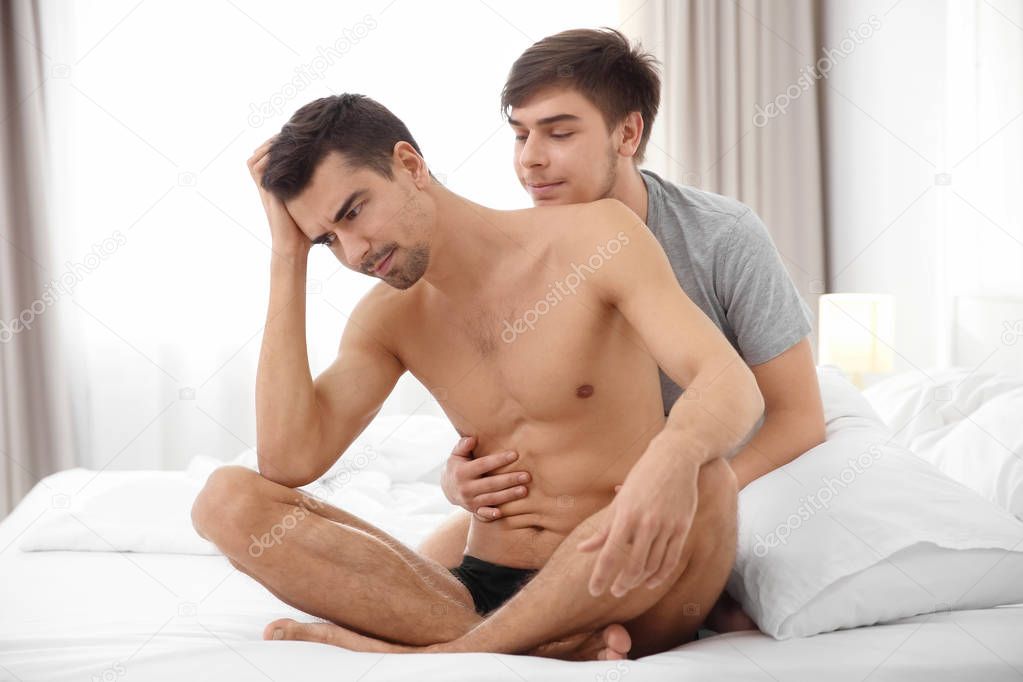 Young gay couple with relationship problems on bed