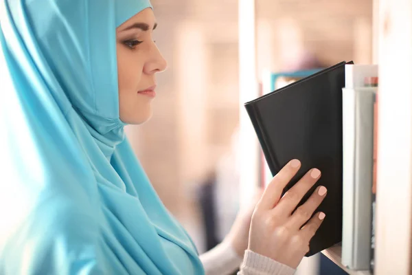 イスラム教徒の学生が図書館の棚から本を選択します — ストック写真