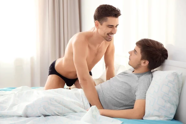 Jonge homo paar samen op bed in lichte kamer — Stockfoto