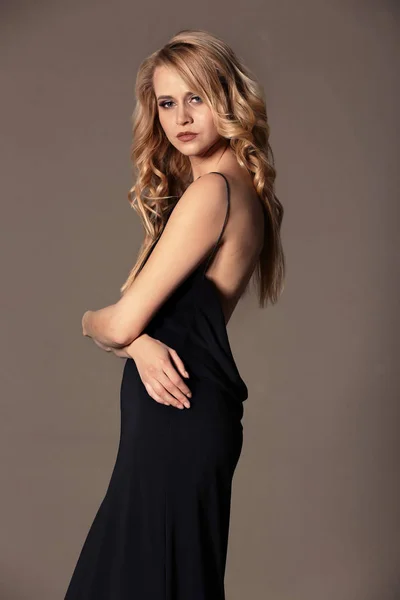 Mooie jonge vrouw met lang golvend haar op kleur achtergrond — Stockfoto