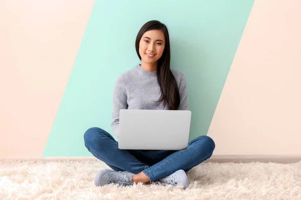 Jeune femme asiatique en utilisant un ordinateur portable sur le sol à l'intérieur — Photo