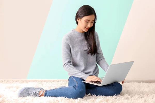 Junge asiatische Frau mit Laptop auf dem Fußboden drinnen — Stockfoto