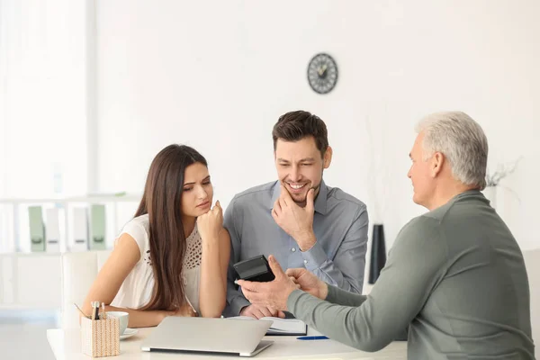 Pareja joven discutiendo plan de pensiones con consultor en oficina — Foto de Stock