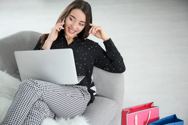 Young woman with laptop talking on phone — Stock Photo, Image
