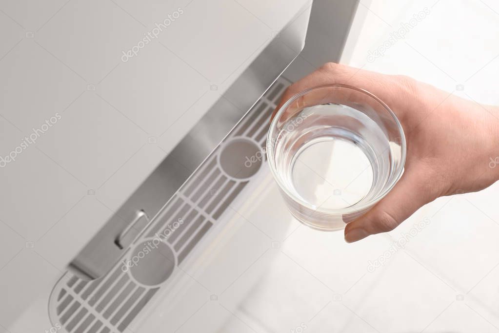 Woman with glass near water cooler 