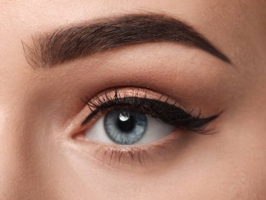 Eye of young woman with beautiful eyebrow after correction, closeup clipart