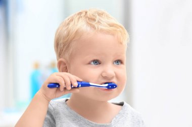 Cute little child cleaning teeth in bathroom clipart