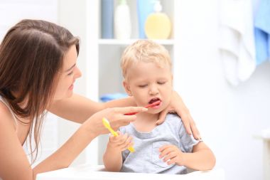 Mother teaching her child how to clean teeth clipart