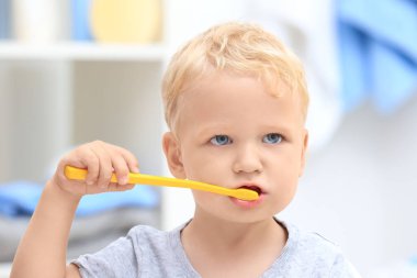 Cute little child cleaning teeth in bathroom clipart