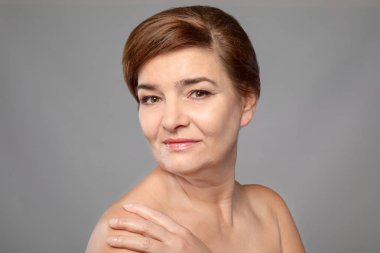 Gri arka plan üzerinde güzel Olgun kadın portresi. Cilt bakım kavramı