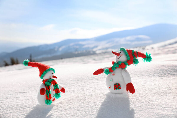 Two toy snowmen at mountain resort on sunny frosty day. Winter vacation
