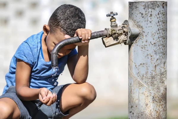 アフリカ系アメリカ人の子供は屋外の蛇口から水を飲む 水の希少性の概念 — ストック写真