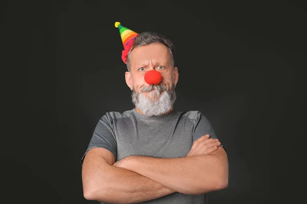 Mature man in funny disguise on dark background. April fool's day celebration