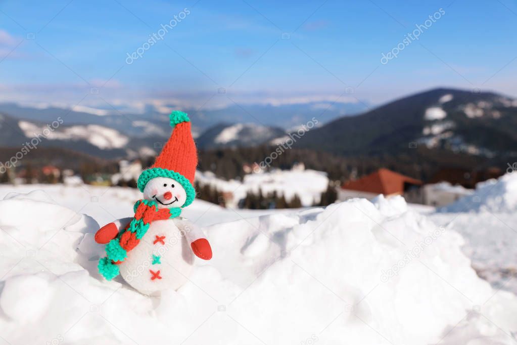 Toy snowman at mountain resort on sunny frosty day. Winter vacation
