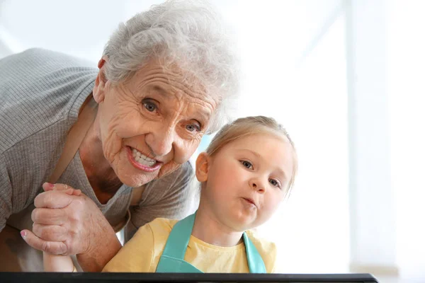 Menina e avó olhando para o forno — Fotografia de Stock