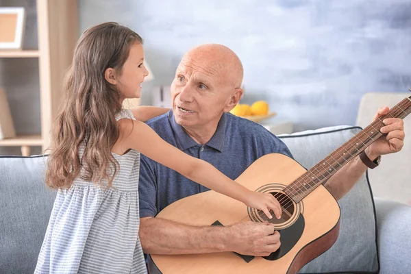 Старший мужчина с внучкой, играющей на гитаре — стоковое фото
