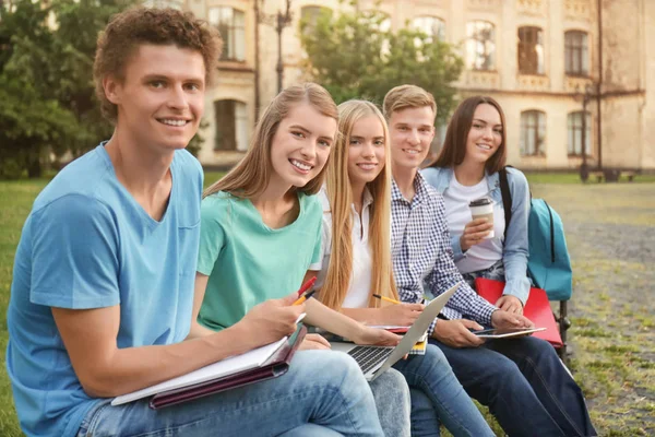 Молодые студенты, сидящие на скамейке — стоковое фото