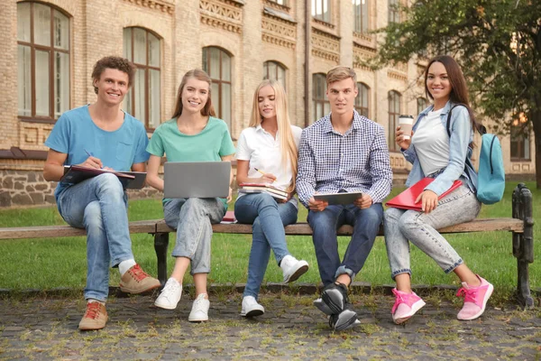 Молодые студенты, сидящие на скамейке — стоковое фото