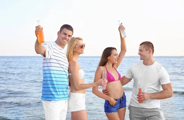 Mladí lidé s nápoji na pláži — Stock fotografie