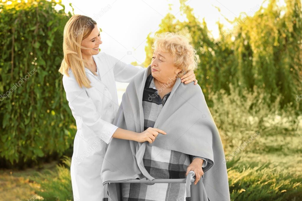 Senior woman with walkers and nurse from care home in park