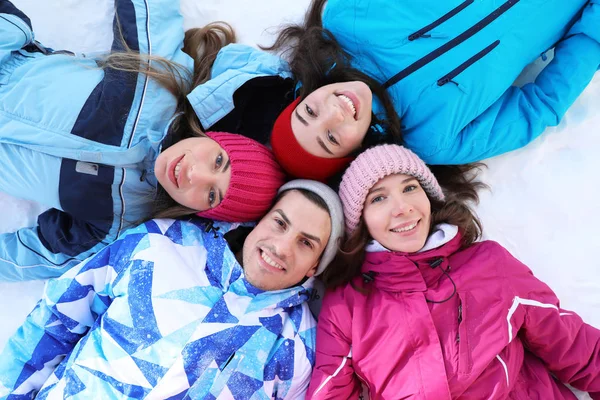 Groep gelukkige vrienden liggend op sneeuw — Stockfoto