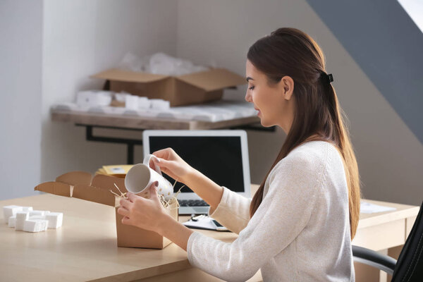 Young woman preparing parcel for shipment to client in home office