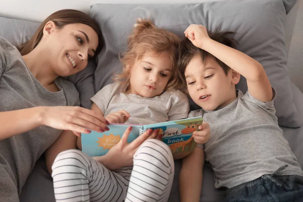 Mother reading bedtime story to children at home