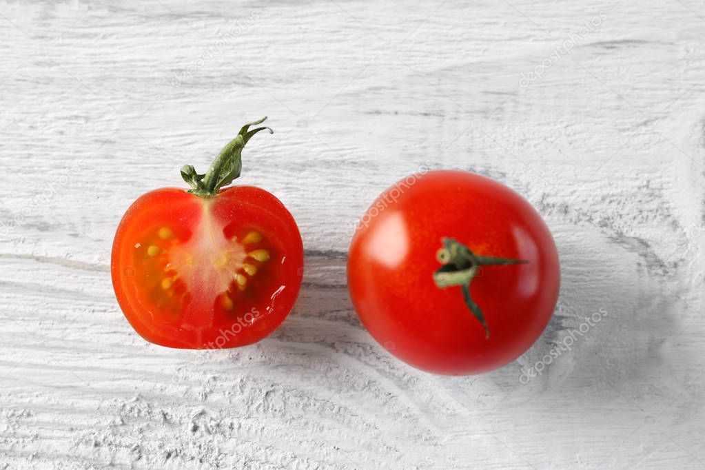 Red tomato and half slice on light wooden background
